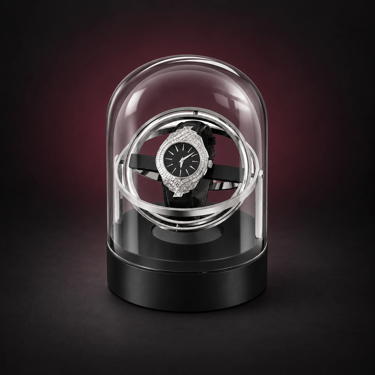Orbit silver-tone gyroscopic watch winder beneath a clear dome on a black base; demonstration watch not included.